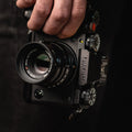 Appareil Fujifilm tenu d’une main sur fond sombre, étiquette discrète sur le boîtier du viseur